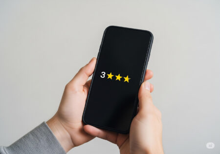 スマートフォンの画面に3つ星評価が表示されているデバイスを両手で持っている様子