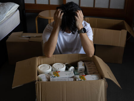 大量のサプリを前に頭を抱える男性